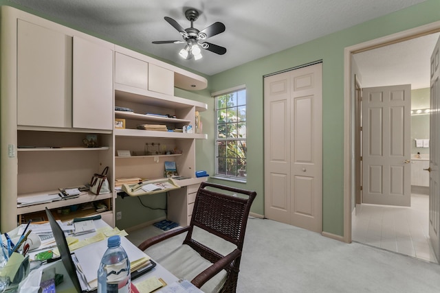 carpeted office space featuring ceiling fan