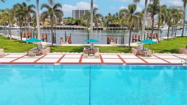 view of pool with a patio, a water view, and a lawn