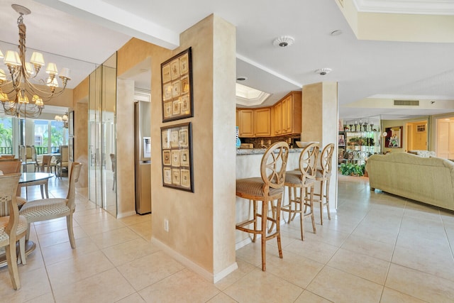 kitchen featuring hanging light fixtures, beamed ceiling, an inviting chandelier, light tile patterned floors, and a kitchen breakfast bar