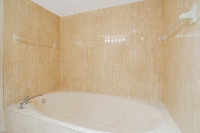 bathroom featuring a relaxing tiled tub and tile walls