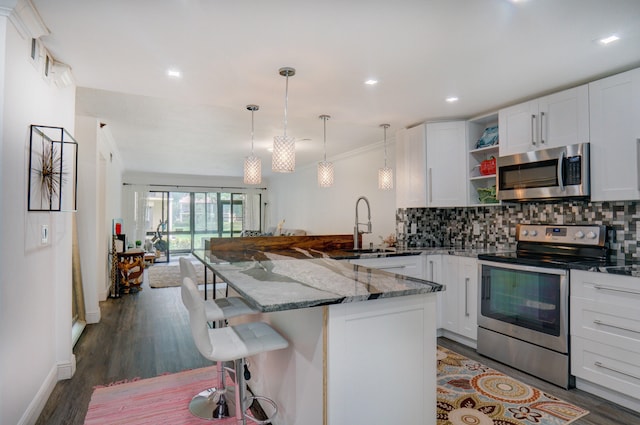 kitchen featuring appliances with stainless steel finishes, a kitchen breakfast bar, decorative light fixtures, white cabinets, and dark hardwood / wood-style floors