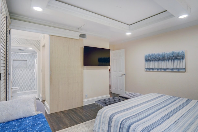 bedroom with a tray ceiling, dark wood-type flooring, and ensuite bath