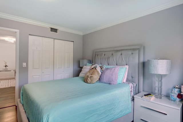 bedroom with crown molding, wood-type flooring, and a closet