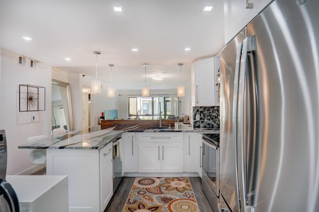 kitchen with white cabinets, kitchen peninsula, hanging light fixtures, and appliances with stainless steel finishes