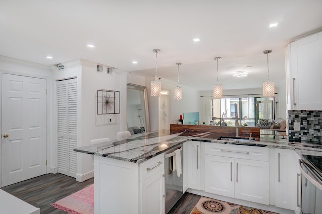 kitchen with appliances with stainless steel finishes, decorative light fixtures, white cabinetry, dark stone counters, and kitchen peninsula