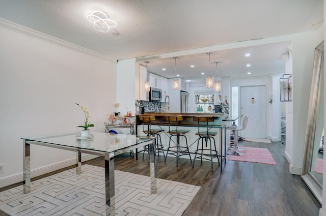 dining space with wood-type flooring, sink, and crown molding