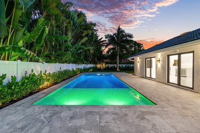 pool at dusk featuring a patio area