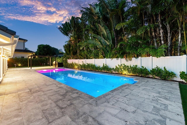 pool at dusk with a patio area