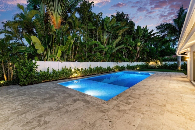 pool at dusk featuring a patio area