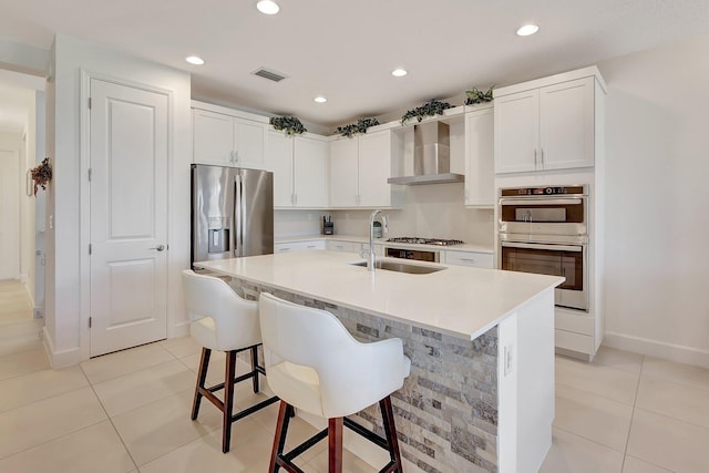 kitchen with white cabinets, sink, wall chimney range hood, and stainless steel appliances