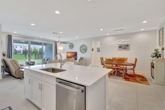 kitchen featuring ceiling fan, stainless steel dishwasher, sink, white cabinetry, and an island with sink