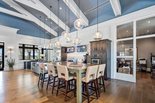 dining space with dark hardwood / wood-style flooring, beam ceiling, a fireplace, and a high ceiling