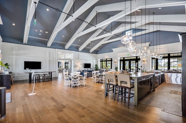 dining room featuring high vaulted ceiling, hardwood / wood-style flooring, and french doors