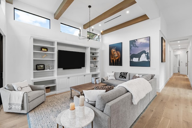 living room with an inviting chandelier, a high ceiling, beamed ceiling, and light hardwood / wood-style flooring