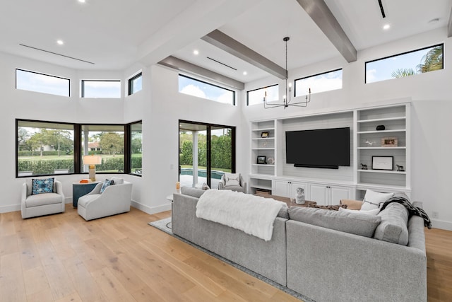 living room with light hardwood / wood-style floors, an inviting chandelier, beam ceiling, and a high ceiling