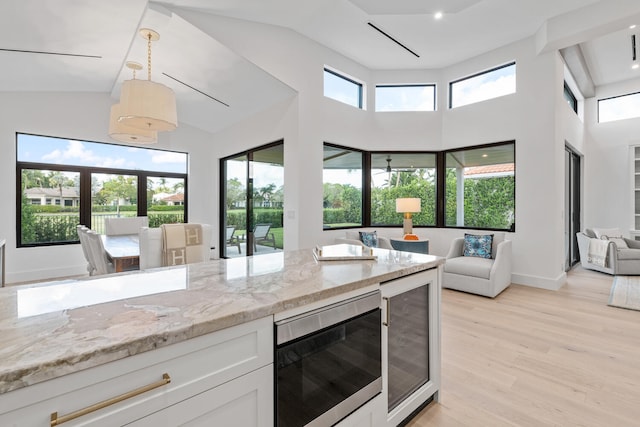 kitchen featuring plenty of natural light, white cabinetry, wine cooler, and light hardwood / wood-style floors