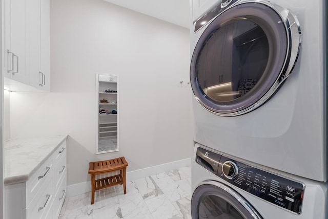 washroom featuring cabinets, stacked washer and dryer, and light tile patterned floors