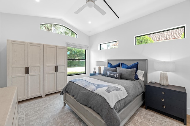 bedroom featuring light hardwood / wood-style floors, multiple windows, ceiling fan, and vaulted ceiling