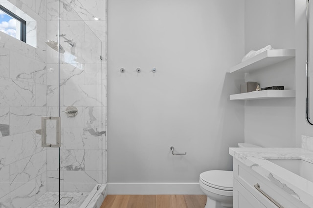 bathroom featuring wood-type flooring, a shower with door, toilet, and vanity