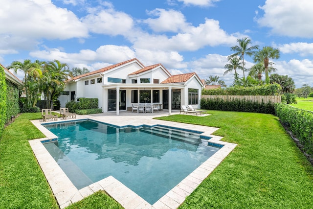 back of property featuring a patio, a yard, and a fenced in pool