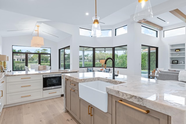 kitchen with sink, a kitchen island with sink, and a wealth of natural light