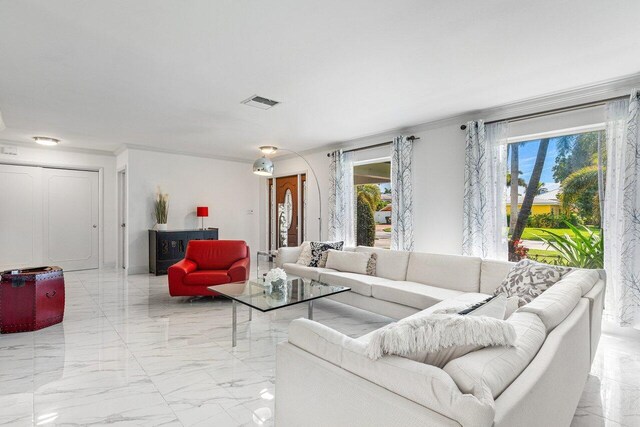 living room featuring light tile patterned flooring, crown molding, and a healthy amount of sunlight