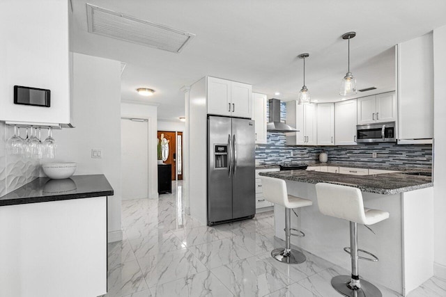 kitchen featuring a kitchen breakfast bar, appliances with stainless steel finishes, white cabinets, and wall chimney exhaust hood