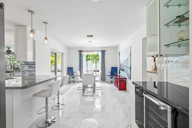 kitchen with marble finish floor, dark stone counters, beverage cooler, and white cabinetry