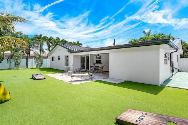 rear view of house with fence, metal roof, a patio, a standing seam roof, and stucco siding