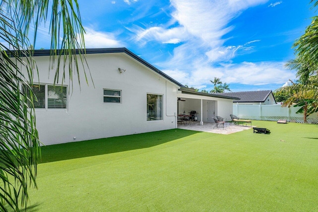 back of house with stucco siding, a yard, a patio area, and fence