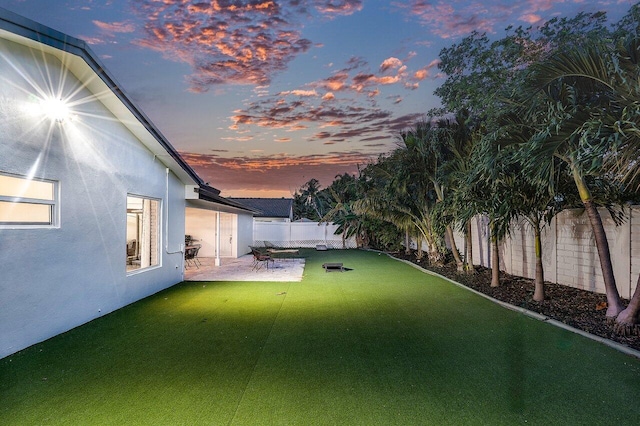 yard at dusk featuring a patio and a fenced backyard