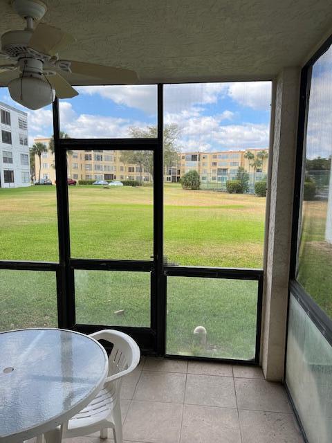 unfurnished sunroom featuring ceiling fan and a healthy amount of sunlight