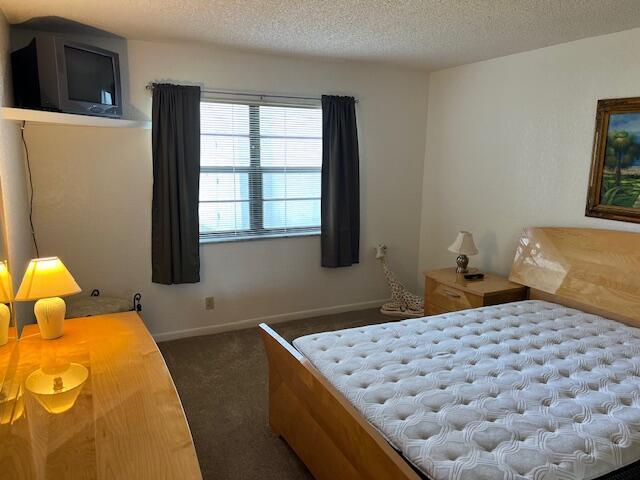 bedroom featuring dark carpet and a textured ceiling