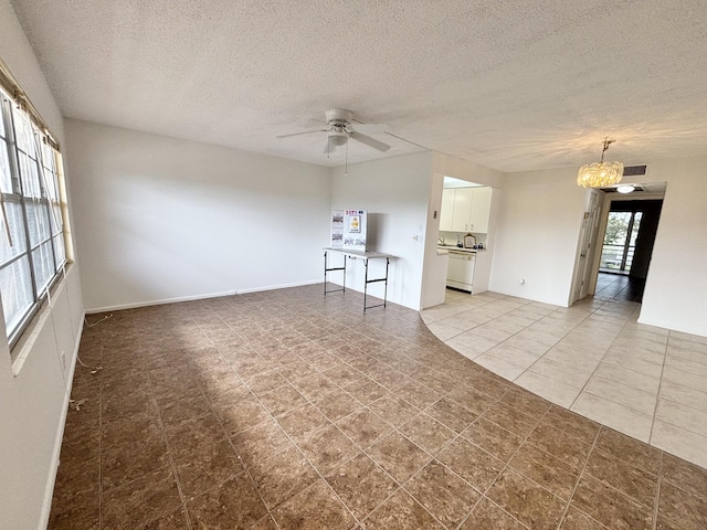 unfurnished living room with ceiling fan with notable chandelier, light tile patterned floors, and a textured ceiling