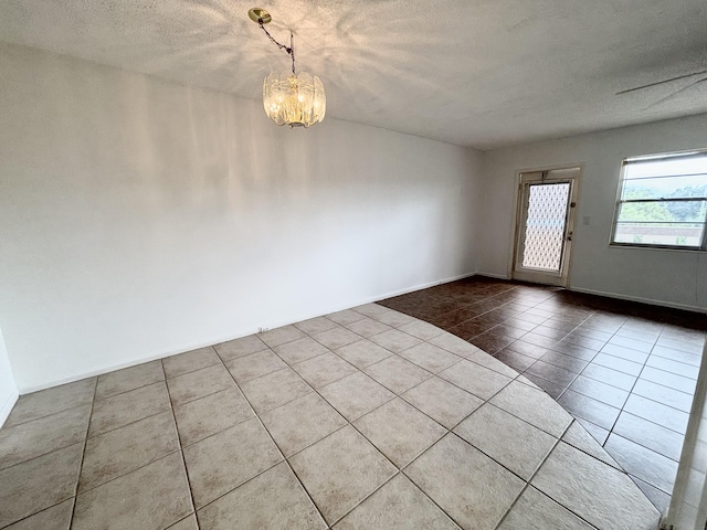 spare room with tile patterned flooring, a textured ceiling, and ceiling fan with notable chandelier