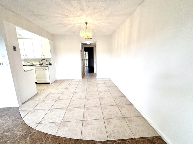 interior space with sink, a textured ceiling, a notable chandelier, and light tile patterned flooring