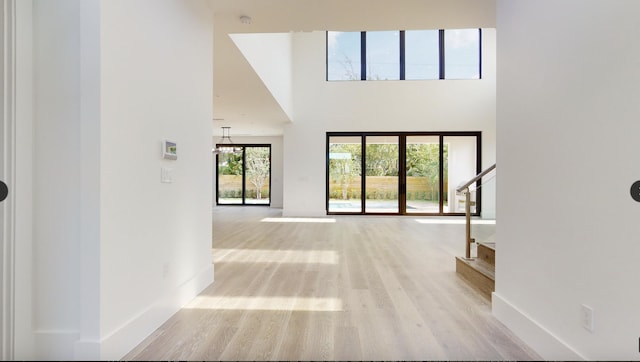 interior space with a towering ceiling and light hardwood / wood-style flooring