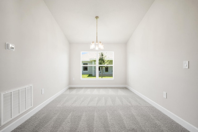 carpeted spare room with a chandelier