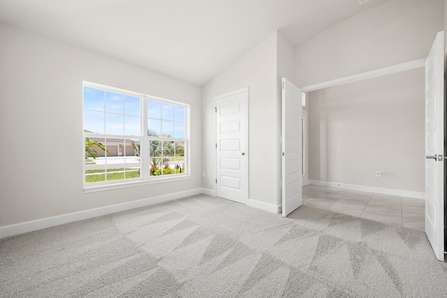 unfurnished bedroom featuring a closet, light colored carpet, and lofted ceiling