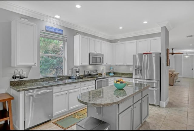 kitchen with light tile patterned floors, stainless steel appliances, white cabinetry, and a kitchen island