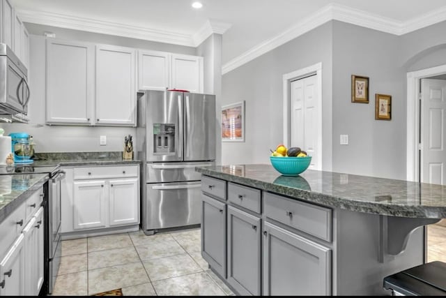 kitchen featuring a center island, stainless steel appliances, ornamental molding, and light tile patterned floors