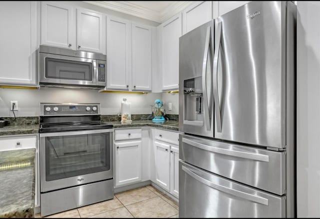 kitchen featuring appliances with stainless steel finishes, white cabinetry, and dark stone counters