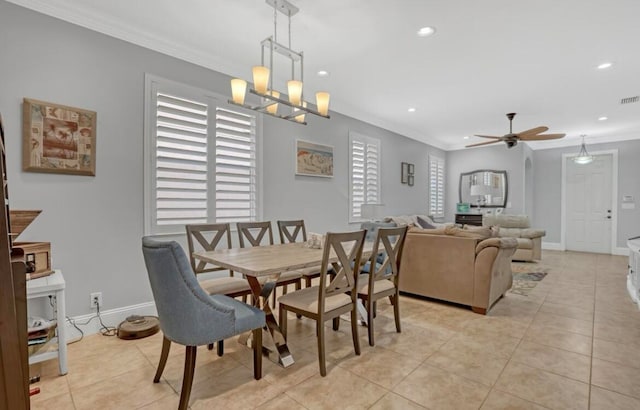 dining space with light tile patterned flooring, ceiling fan with notable chandelier, and ornamental molding