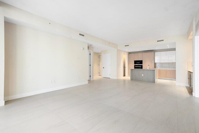 kitchen with black appliances, sink, a center island with sink, light tile patterned floors, and backsplash