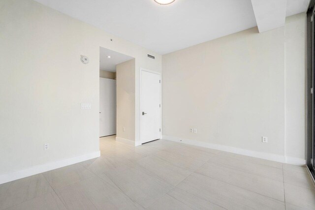 spare room with floor to ceiling windows and light tile patterned floors