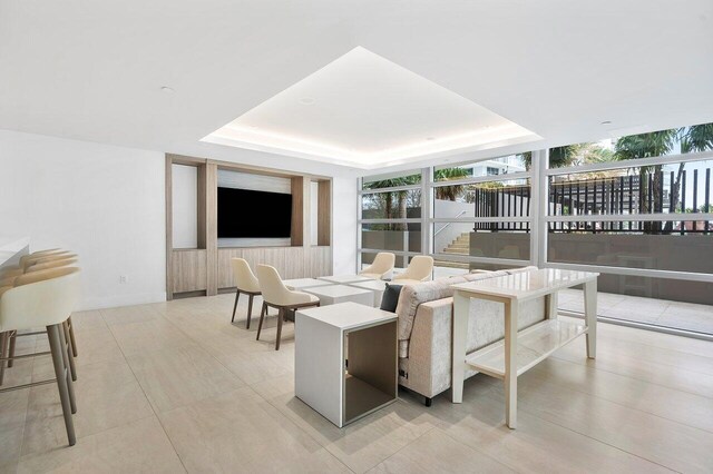 living room featuring expansive windows, a tray ceiling, and light tile patterned floors