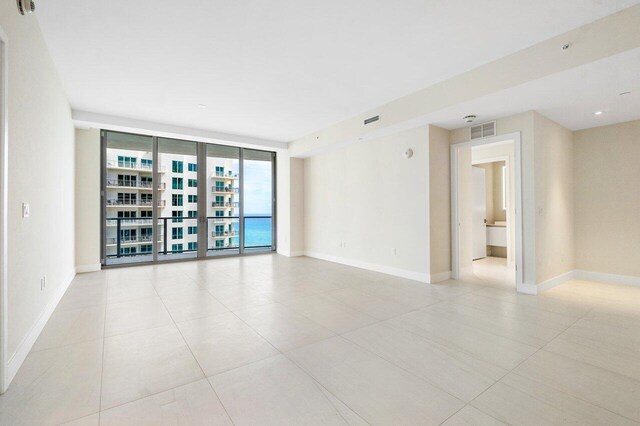 bedroom featuring a wall of windows, light tile patterned floors, and access to outside