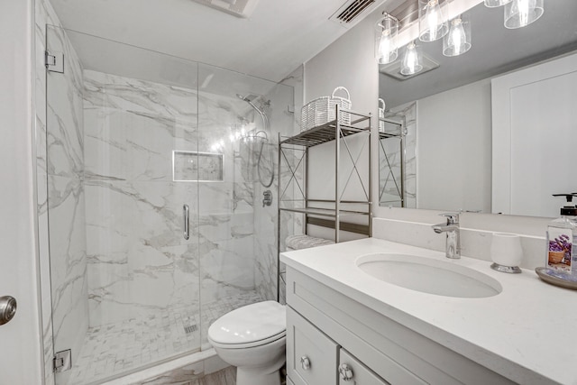 bathroom featuring a shower with shower door, vanity, and toilet