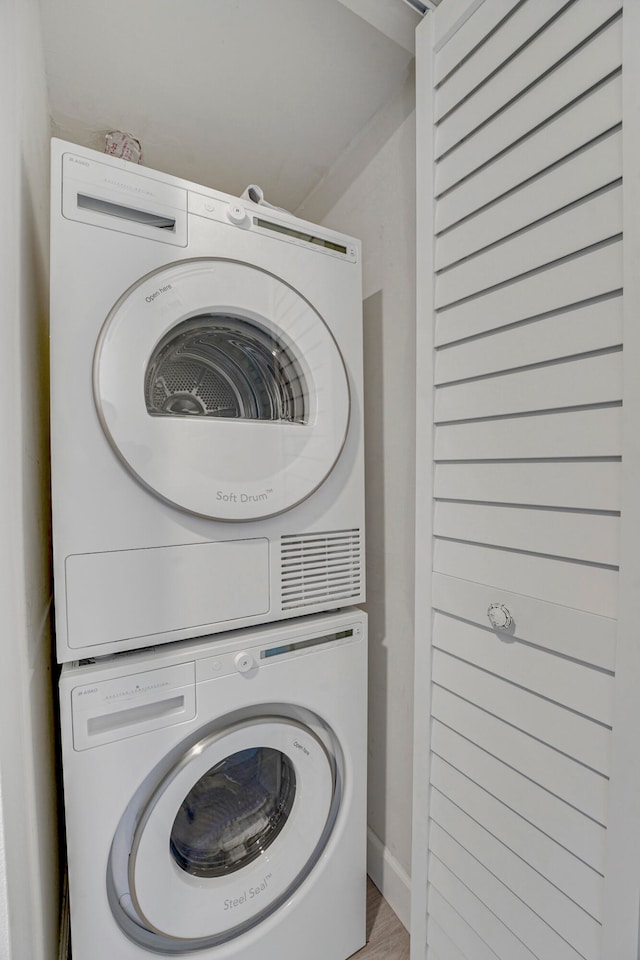 laundry area featuring stacked washer / dryer and wood-type flooring