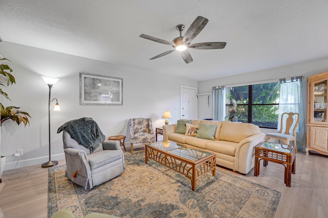 living room with light hardwood / wood-style floors, a textured ceiling, and ceiling fan